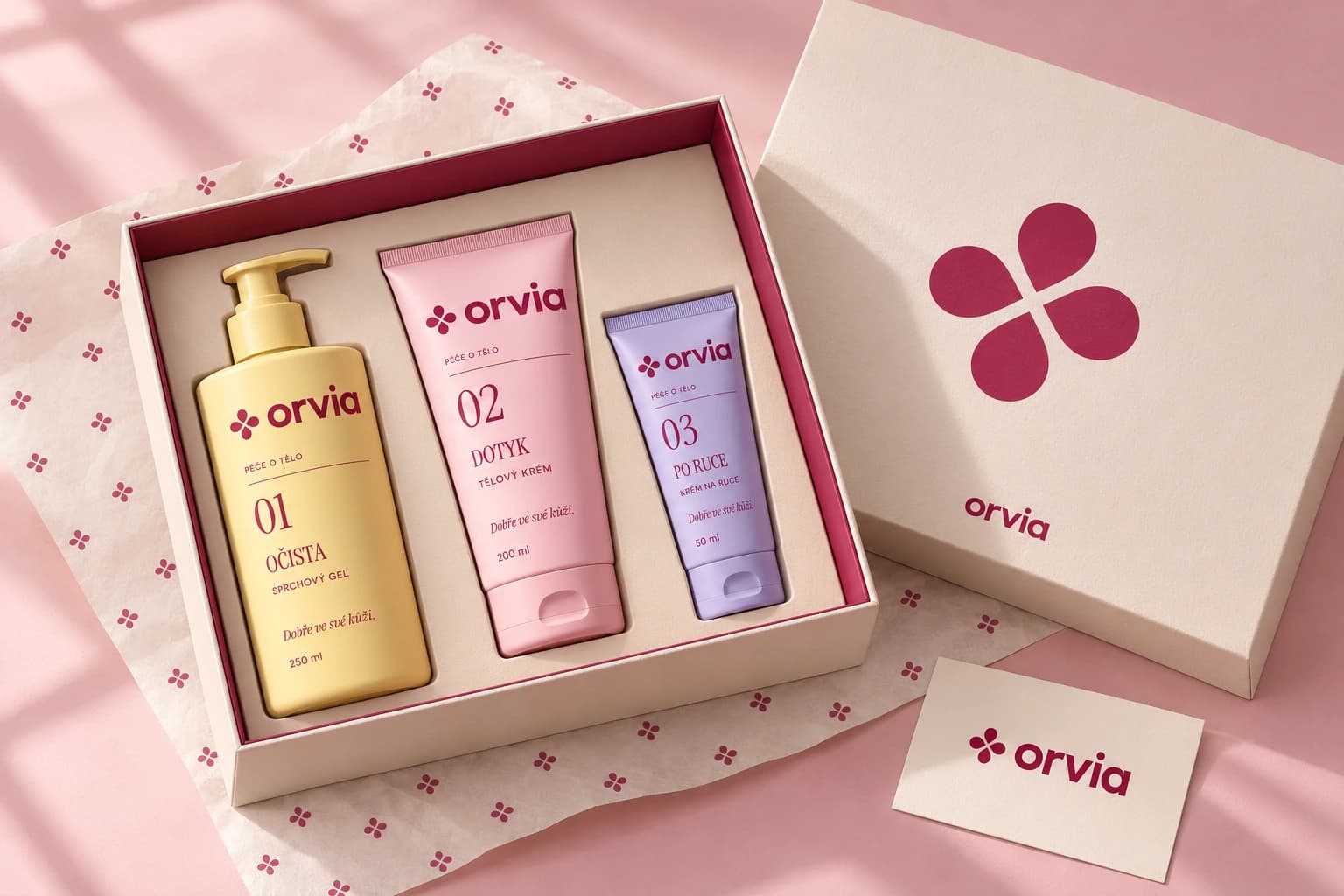 Modelová otevřená dárková krabice se třemi produkty ORVIA, samostatným symbolem a značkovým papírem.